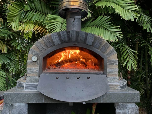 Barbecue extérieur en briques réfractaires installé dans un jardin verdoyant